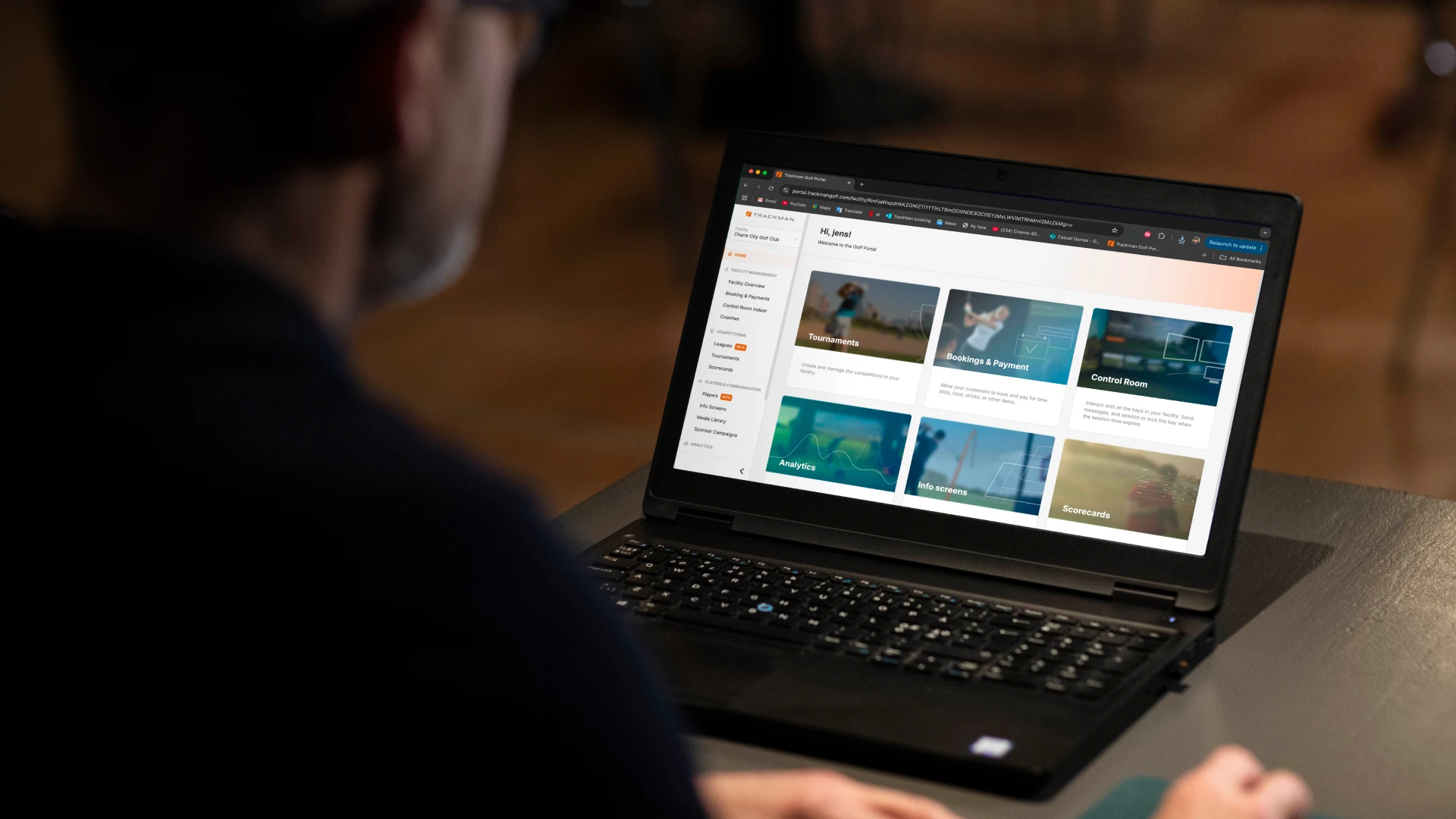 Person using a laptop displaying an online learning platform with various course thumbnails on the screen in a dimly lit room.