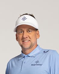 Ian Poulter in a light blue polo and white visor, smiling against a neutral background.