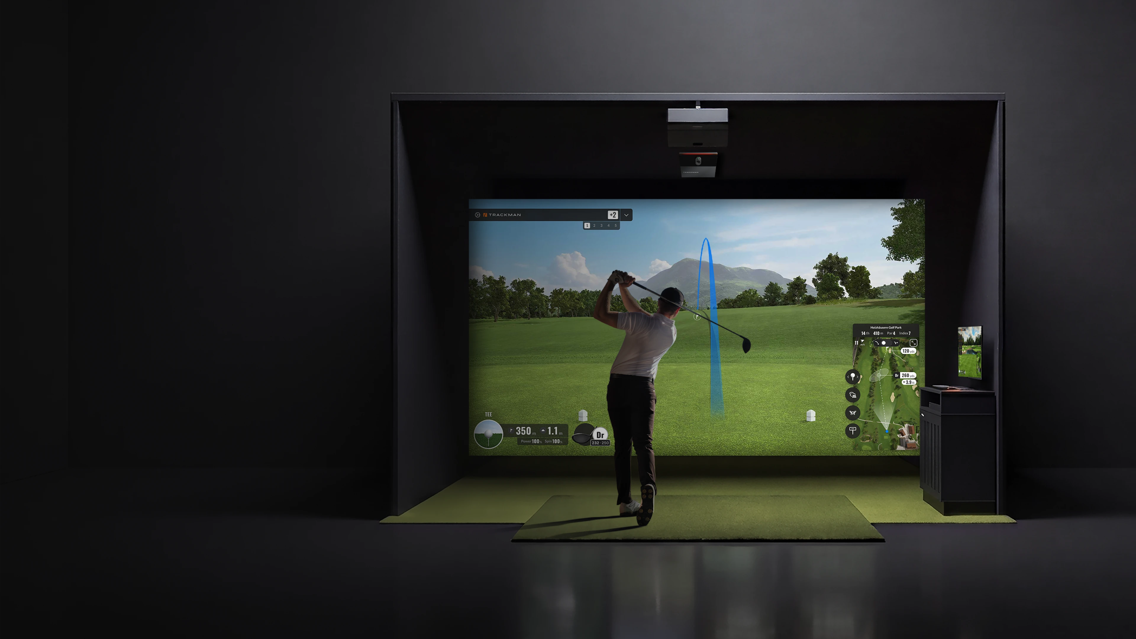 Person playing golf in an indoor simulator, displaying a green course and shot trajectory on a screen.